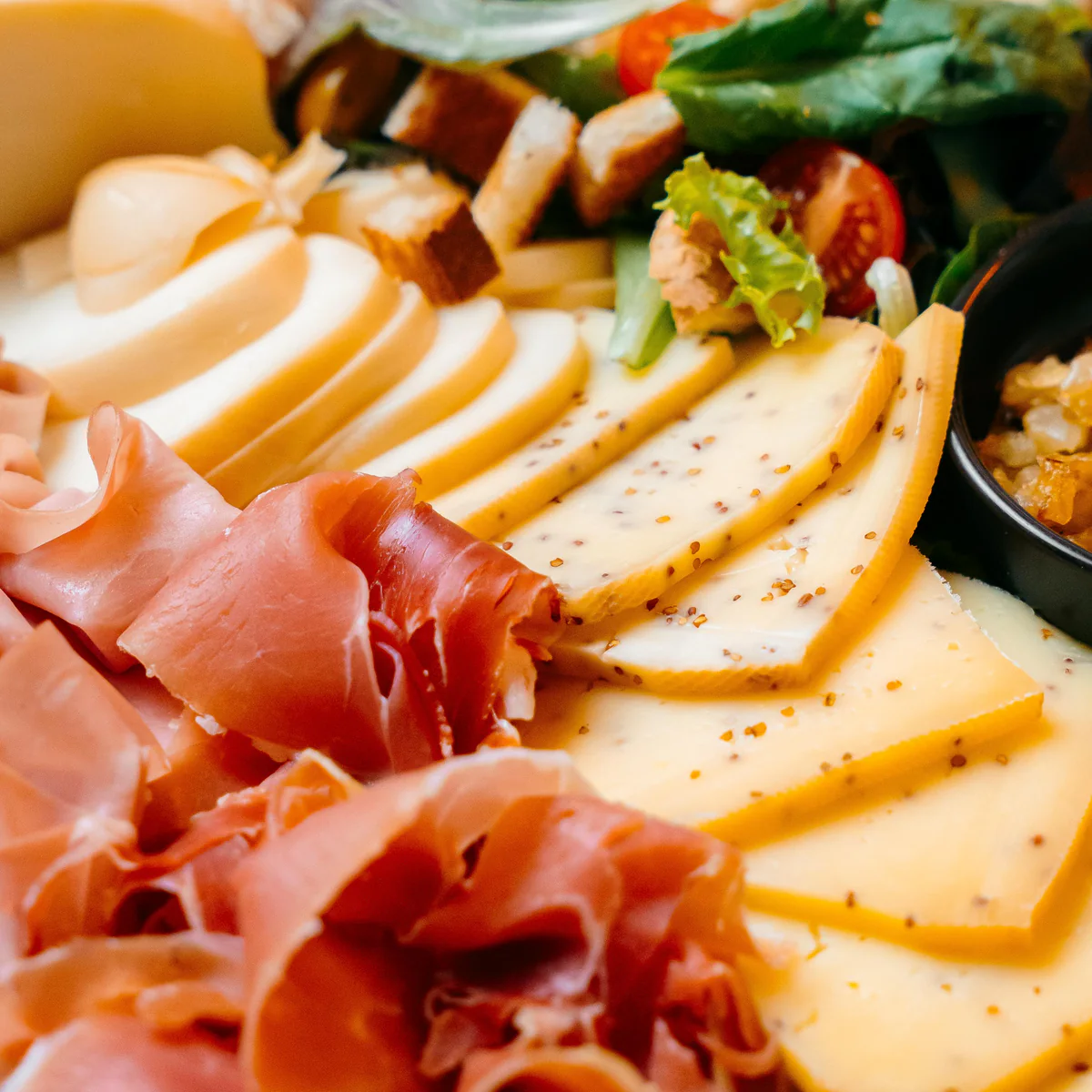 Gros plan sur les fromages en tranches et les charcuteries de la planche