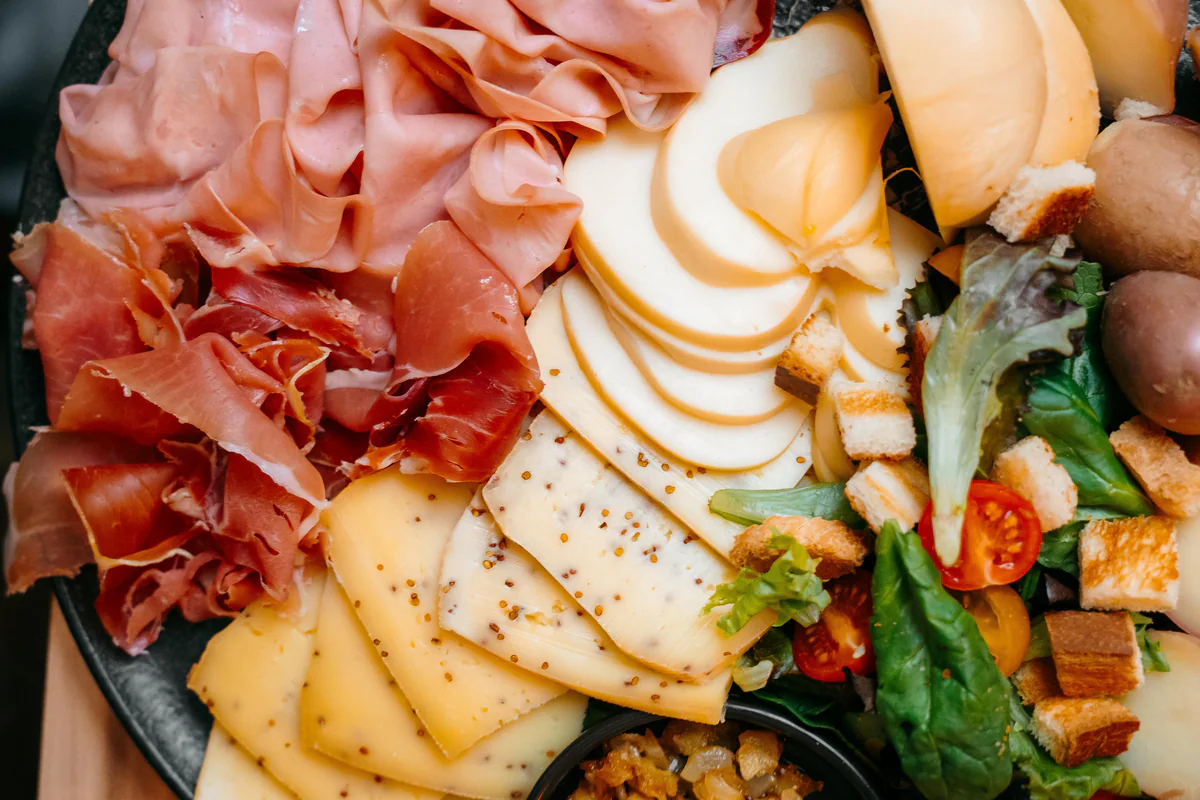 Planche de charcuteries, de fromages en tranches et de salade, vue de dessus