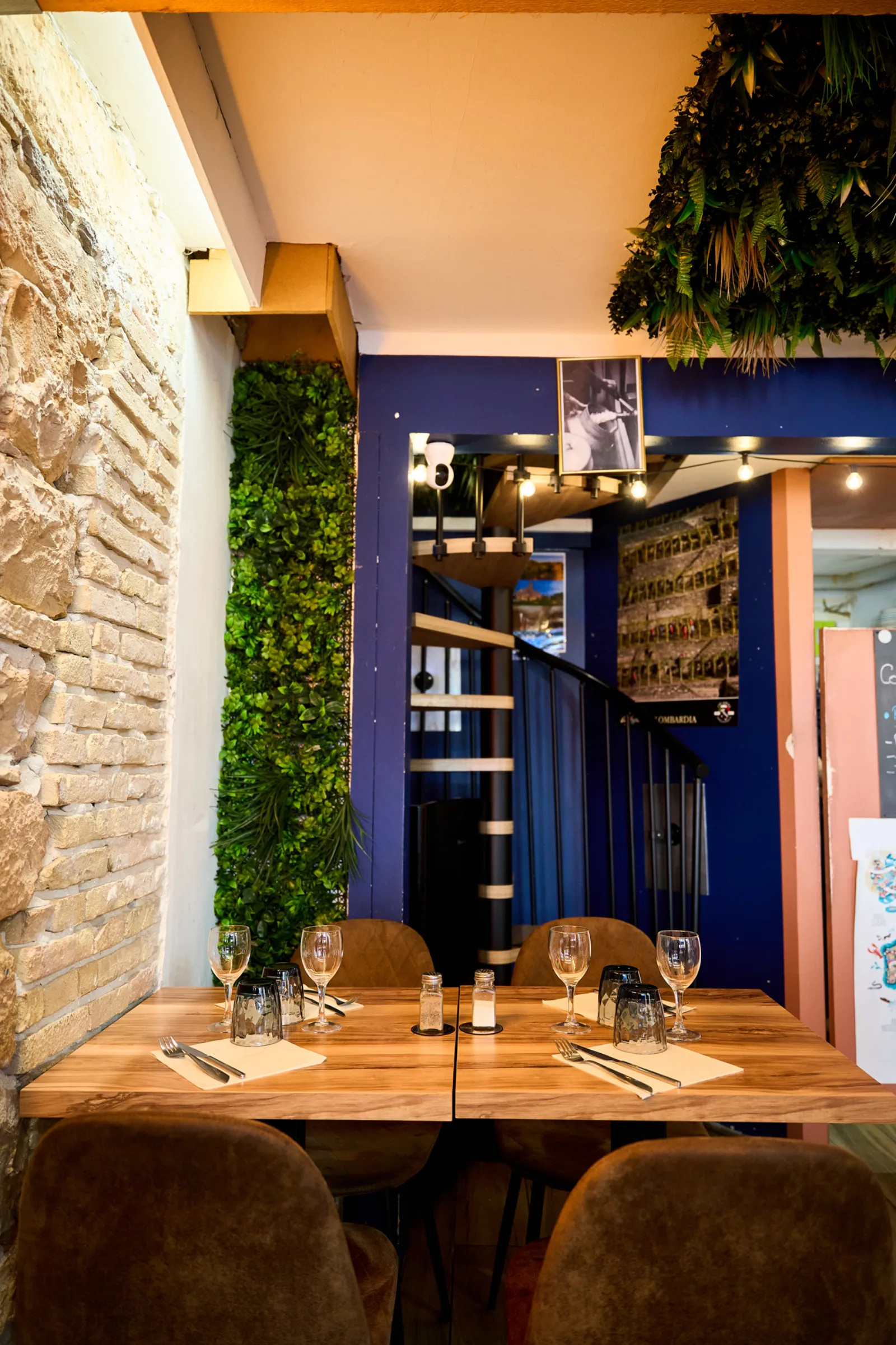 Salle du restaurant La Mozzarelle avec mur en pierres et escalier en colimaçon